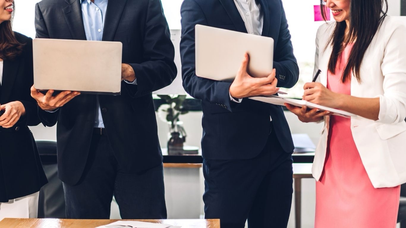 Tim kerja perusahaan membawa laptop dan dokumen di kantor
